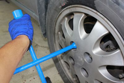 Cropped hand of mechanic removing tire of car