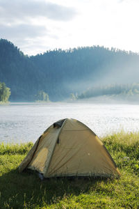 Tourist tent on river bank. camping tent near mountain river. local tourism, weekend at nature.