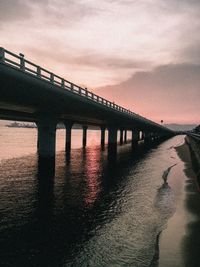 Bridge over sea against sky during sunset