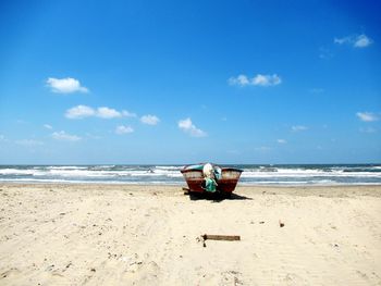 Deck chairs on beach against sky