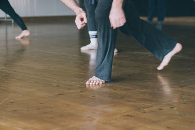 Low section of male ballet dancer practicing on hardwood floor in studio