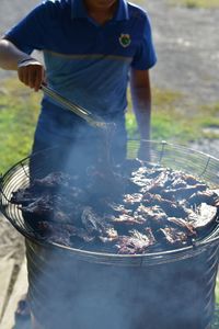 Close-up of man standing by barbecue grill