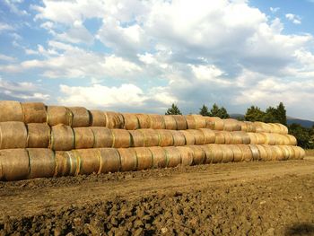 Stack of hay bales on field against sky in umbria, italy