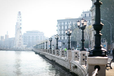 Bridge over river by buildings in city against sky