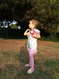 Full length of girl looking away while standing on grass