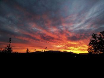 Silhouette landscape against orange sky