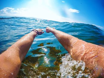 Close-up of hand by sea against sky