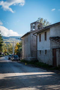 Cars on road by buildings against sky