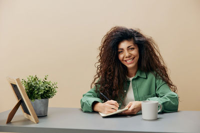 Portrait of young woman using mobile phone on table