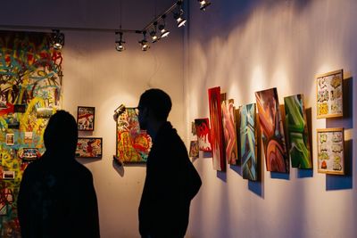 Rear view of women standing against multi colored wall