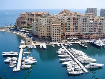 High angle view of sailboats moored in harbor by buildings against sky