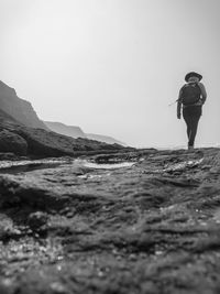 Rear view of man walking on shore against sky