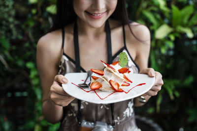 Midsection of woman holding food in plate