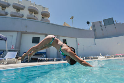 Man jumping in swimming pool against sky