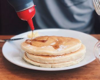 Honey pouring on pancakes in plate