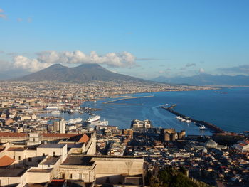 Aerial view of townscape by sea against sky