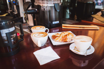 Coffee cups and croissant on table at restaurant