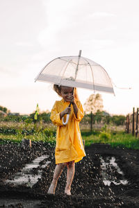 Woman standing on wet umbrella during rainy season