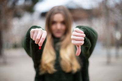 Close-up of woman with pill showing thumbs down 