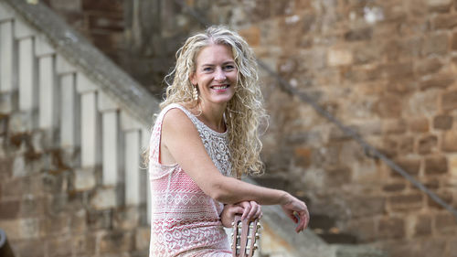 Portrait of smiling woman against wall