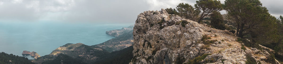 Panoramic view of rocks by sea against sky