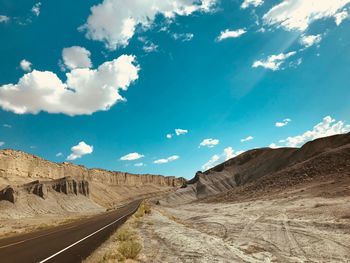 Empty road leading towards mountains against sky