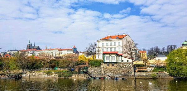 Buildings by river against sky