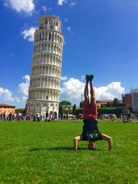 Man practicing headstand against leaning tower of pisa