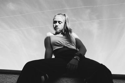 Portrait of young woman looking away against sky