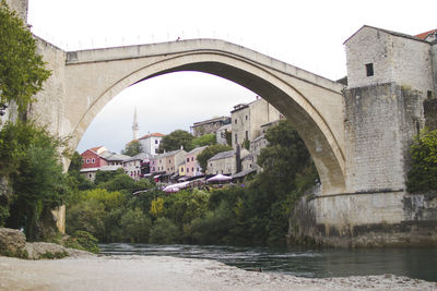 Arch bridge over river against buildings