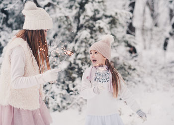 Sisters holding sparklers during winter