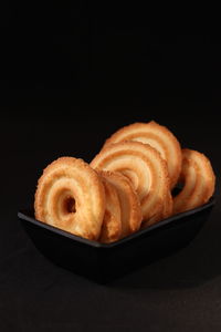 Close-up of bread in plate against black background