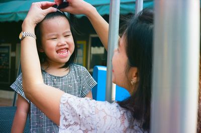 Mother tying daughter hair