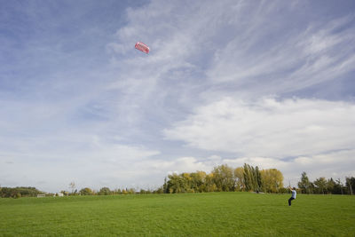 Man flying over field against sky