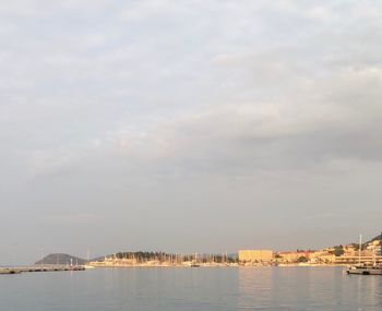 City buildings by sea against sky