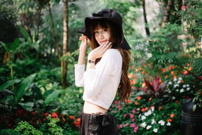 Portrait of young woman standing against plants