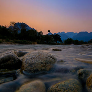 Surface level of rocks on shore against sky during sunset