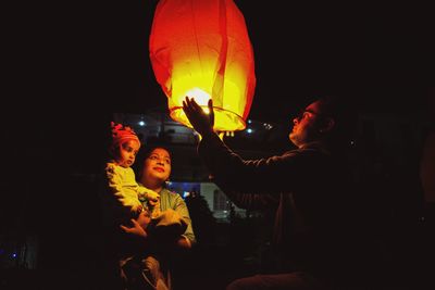 Man holding paper lantern in hand during night outdoors