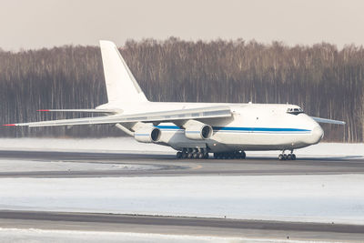 Huge white wide-body cargo airplane taxing on runway for take off at sunny winter day.