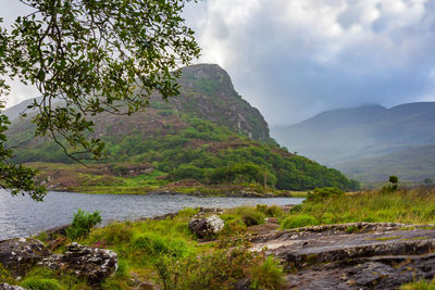 Scenic view of river by mountains against sky