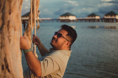 Side view of young man swinging above the sea