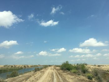 Dirt road along landscape against sky