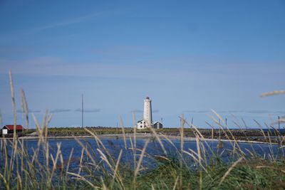 Lighthouse by sea against sky