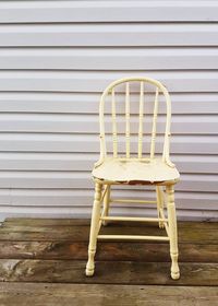 Empty chair on wooden table against wall