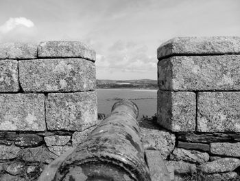 Stone wall by sea against sky