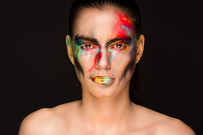 Portrait of woman with face paint against black background