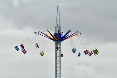 Low angle view of chain swing ride against sky