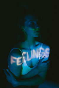 Young woman looking away while standing against black background