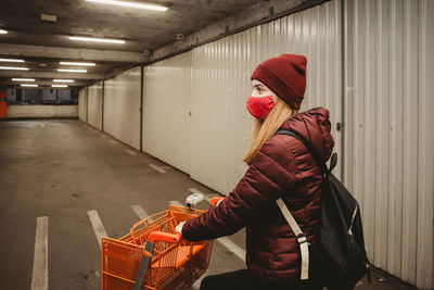 Midsection of woman standing against wall holding shopping cart