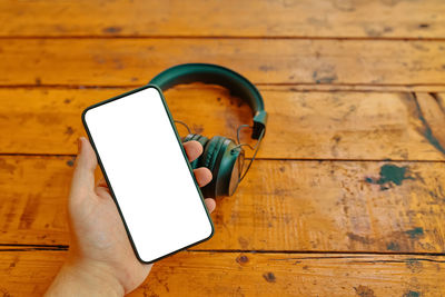 High angle view of hand holding smart phone on table